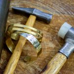 Handgefertigte Armbänder eines Workshop-Teilnehmenden neben Goldschmiedewerkzeugen in Liestal.