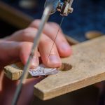 Hände führen eine Goldschmiedesäge am Werktisch während eines Schmuckkurses in Liestal.