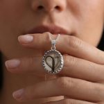 Eine Hand hält den VIVIDA Anhänger nah am Gesicht – so ist die tatsächliche Grösse gut zu erkennen.